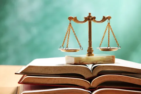 Brass scales of justice placed on an open legal textbook.