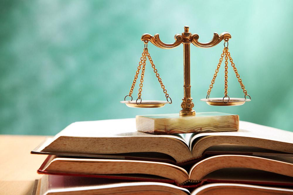 Brass scales of justice placed on an open legal textbook.